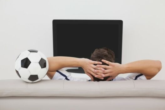 Mand med fodboldtrøje foran sit TV